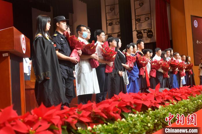 图为毕业生代表向教职员工代表献花。 吕明 摄