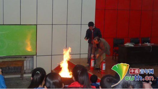 三营中学政教处主任和支教团成员为学生示范灭火器的正确使用方法。巫俊供图